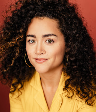 woman with yellow top and curly hair smiling